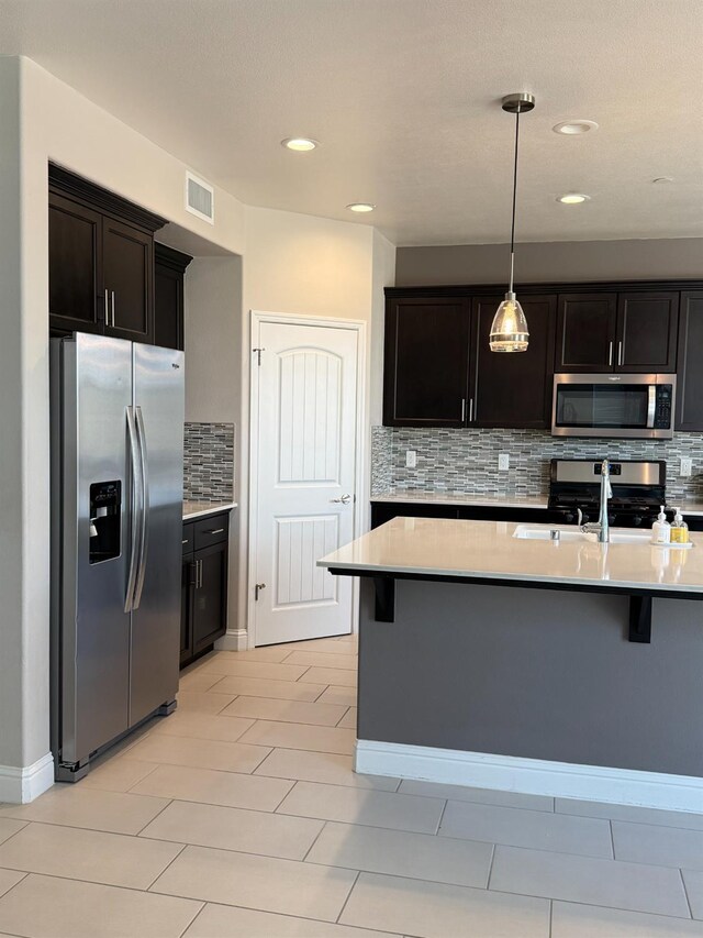 3963 Morris Ave, Clovis, CA 93619 - kitchen featuring stainless steel appliances, decorative backsplash, a kitchen breakfast bar, light countertops, and recessed lighting