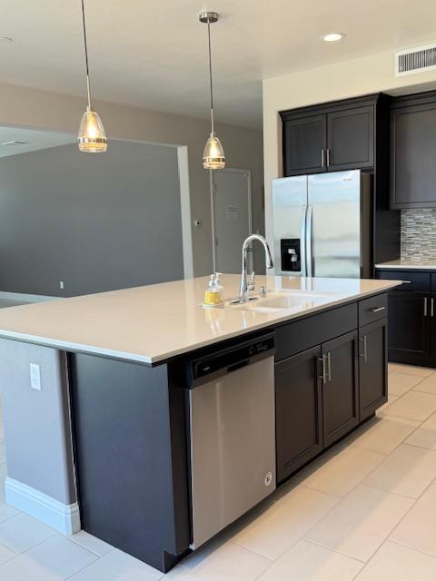 3963 Morris Ave, Clovis, CA 93619 - kitchen with stainless steel appliances, a kitchen island with sink, light countertops, decorative light fixtures, and recessed lighting