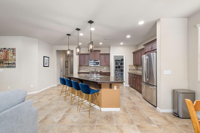 3143 Celeste Ave, Clovis, CA 93619 - kitchen with appliances with stainless steel finishes, a breakfast bar, backsplash, recessed lighting, and a kitchen island with sink