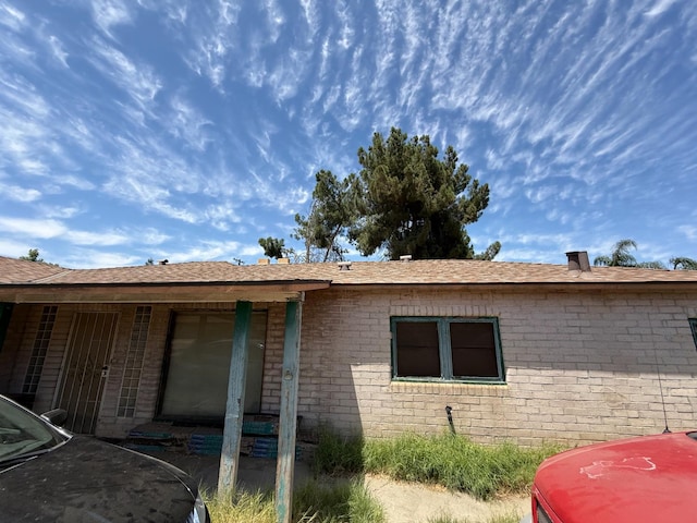 5561 E Indianapolis Ave, Fresno, CA 93727 - view of side of home featuring brick siding and roof with shingles