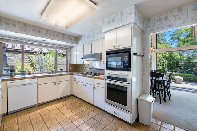 5630 N El Adobe Dr, Fresno, CA 93711 - kitchen featuring stainless steel appliances, under cabinet range hood, tile counters, white cabinets, and light tile patterned floors