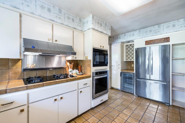 5630 N El Adobe Dr, Fresno, CA 93711 - kitchen with black appliances, wine cooler, under cabinet range hood, tile counters, and tasteful backsplash