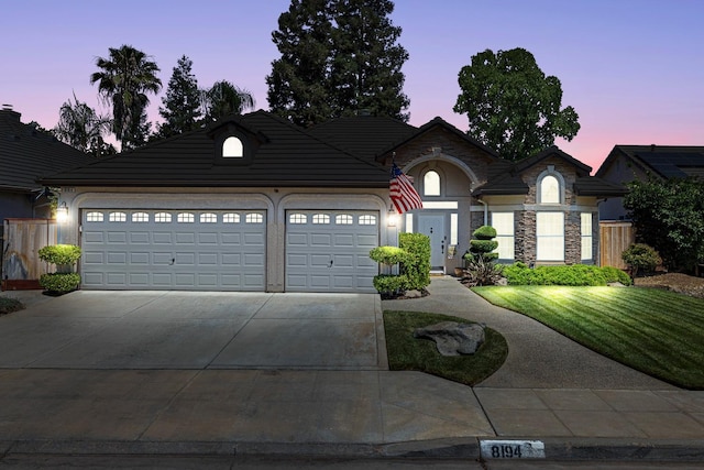 8194 N 5th St, Fresno, CA 93720 - view of front facade featuring a garage, concrete driveway, a front lawn, stone siding, and stucco siding