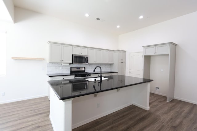 879 Hermosa Ave, Clovis, CA 93619 - kitchen featuring stainless steel appliances, dark countertops, decorative backsplash, wood finished floors, and recessed lighting