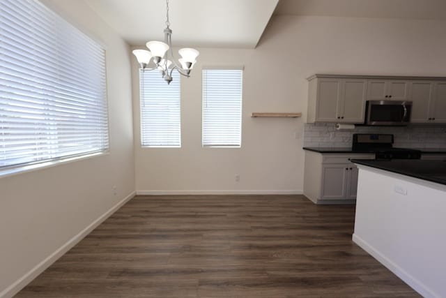 879 Hermosa Ave, Clovis, CA 93619 - kitchen featuring stainless steel microwave, stove, a chandelier, dark countertops, and decorative backsplash