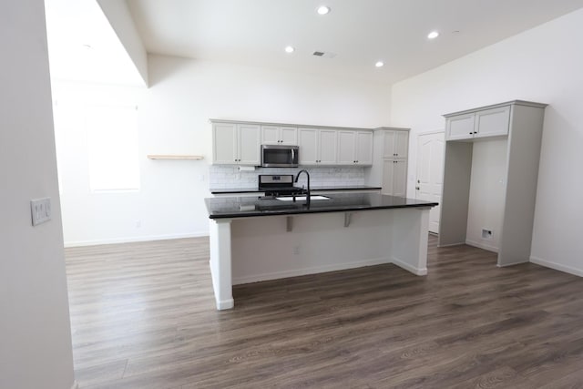 879 Hermosa Ave, Clovis, CA 93619 - kitchen featuring appliances with stainless steel finishes, dark countertops, an island with sink, dark wood-style floors, and recessed lighting