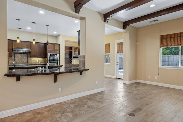 5857 W Modoc, Visalia, CA 93291 - kitchen featuring under cabinet range hood, a kitchen breakfast bar, tasteful backsplash, dark stone countertops, and stainless steel double oven