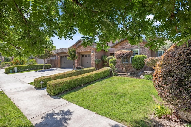 5857 W Modoc, Visalia, CA 93291 - view of front of home with concrete driveway, stone siding, a front yard, and a garage