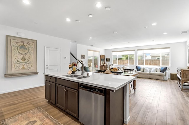 4086 Dennis Ave, Clovis, CA 93619 - kitchen featuring stainless steel dishwasher, light countertops, light wood finished floors, dark brown cabinets, and a center island with sink