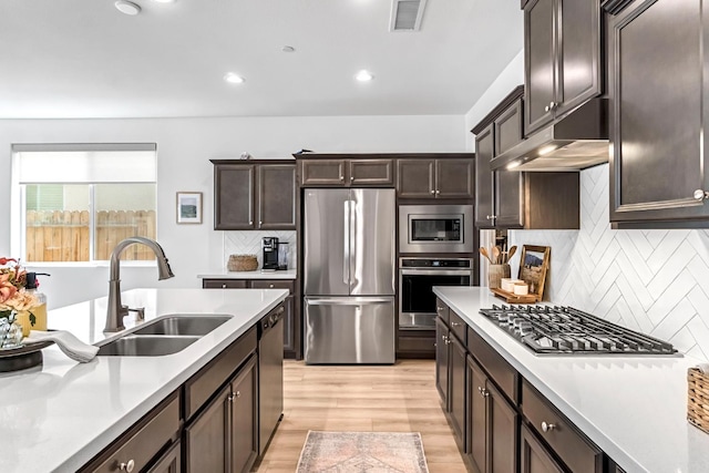 4086 Dennis Ave, Clovis, CA 93619 - kitchen with stainless steel appliances, light countertops, dark brown cabinetry, under cabinet range hood, and tasteful backsplash