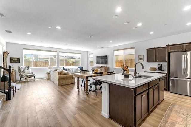 4086 Dennis Ave, Clovis, CA 93619 - kitchen with appliances with stainless steel finishes, light countertops, dark brown cabinets, light wood-style flooring, and open floor plan
