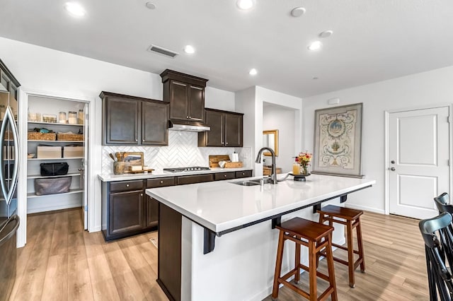 4086 Dennis Ave, Clovis, CA 93619 - kitchen featuring light wood finished floors, a kitchen breakfast bar, light countertops, dark brown cabinets, and recessed lighting