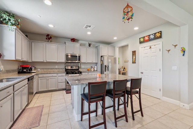 7330 E Princeton Ave, Fresno, CA 93737 - kitchen with stainless steel appliances, light tile patterned floors, recessed lighting, a kitchen island, and a kitchen bar