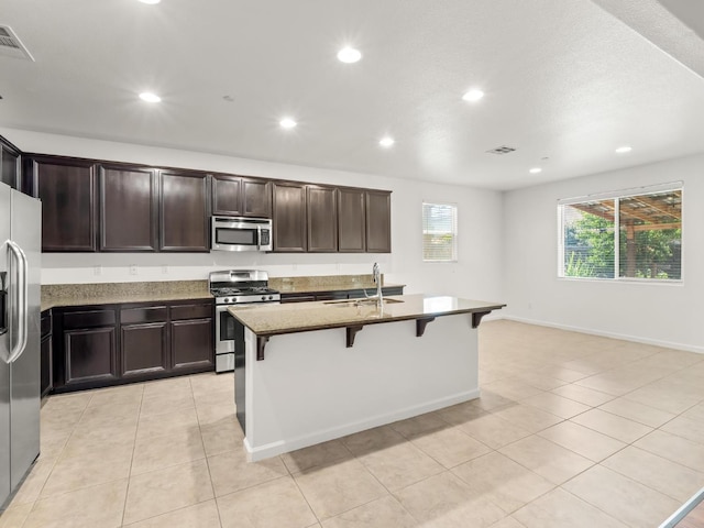 3807 N Pearwood Ave, Fresno, CA 93727 - kitchen featuring appliances with stainless steel finishes, recessed lighting, a kitchen breakfast bar, light tile patterned floors, and stone countertops