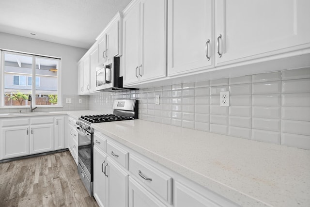 2720 San Jose Ave, Clovis, CA 93611 - kitchen with appliances with stainless steel finishes, light wood finished floors, white cabinets, backsplash, and light stone counters