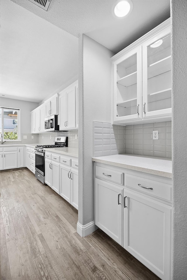 2720 San Jose Ave, Clovis, CA 93611 - kitchen with appliances with stainless steel finishes, light wood-style flooring, decorative backsplash, light countertops, and a textured ceiling