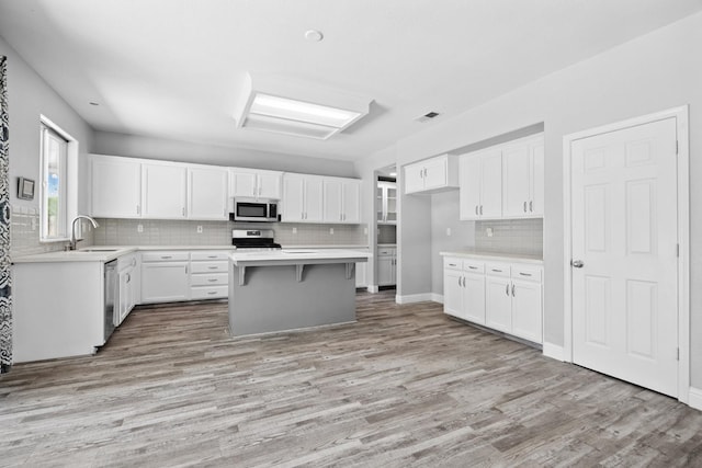 2720 San Jose Ave, Clovis, CA 93611 - kitchen featuring stainless steel appliances, light wood finished floors, tasteful backsplash, white cabinetry, and a kitchen island