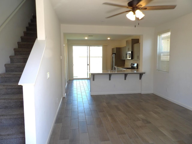 3725 Graystoke Way, Clovis, CA 93619 - kitchen featuring stainless steel appliances, a ceiling fan, a breakfast bar, a peninsula, and dark wood-style flooring
