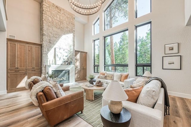42732 Granite Cir, Shaver Lake, CA 93664 - living room featuring a high ceiling, a fireplace, light wood-style flooring, and a chandelier