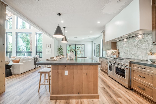42732 Granite Cir, Shaver Lake, CA 93664 - kitchen with double oven range, dark countertops, custom exhaust hood, a breakfast bar, and decorative backsplash