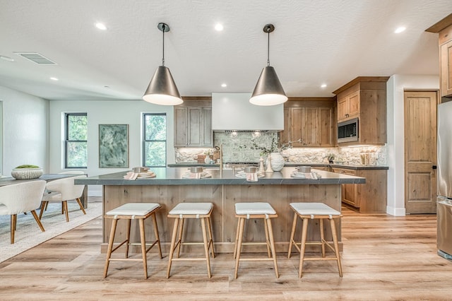 42732 Granite Cir, Shaver Lake, CA 93664 - kitchen featuring stainless steel appliances, dark countertops, custom exhaust hood, light wood finished floors, and tasteful backsplash