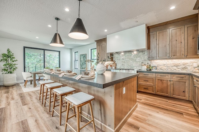 42732 Granite Cir, Shaver Lake, CA 93664 - kitchen with dark countertops, custom exhaust hood, a center island, decorative backsplash, and a kitchen breakfast bar