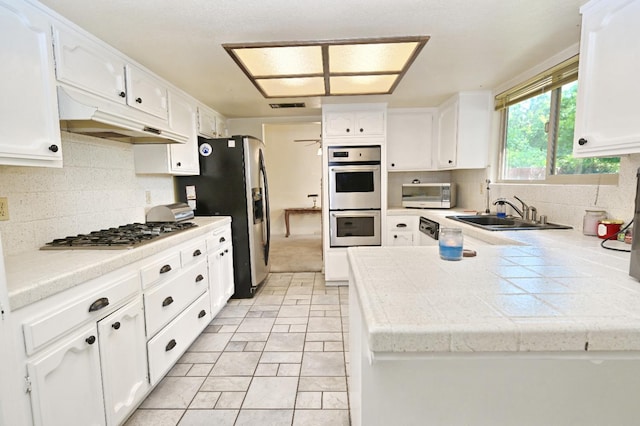110 N Terry Ave, Clovis, CA 93612 - kitchen with stainless steel appliances, under cabinet range hood, white cabinetry, a peninsula, and tasteful backsplash