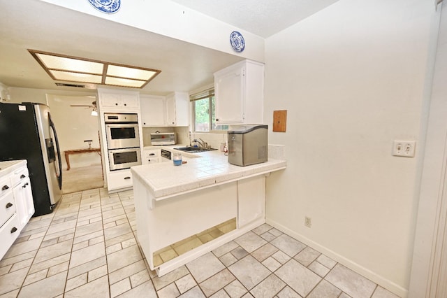 110 N Terry Ave, Clovis, CA 93612 - kitchen with stainless steel appliances, a peninsula, white cabinetry, a ceiling fan, and decorative backsplash