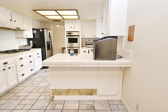 110 N Terry Ave, Clovis, CA 93612 - kitchen with under cabinet range hood, stainless steel appliances, a peninsula, decorative backsplash, and white cabinetry