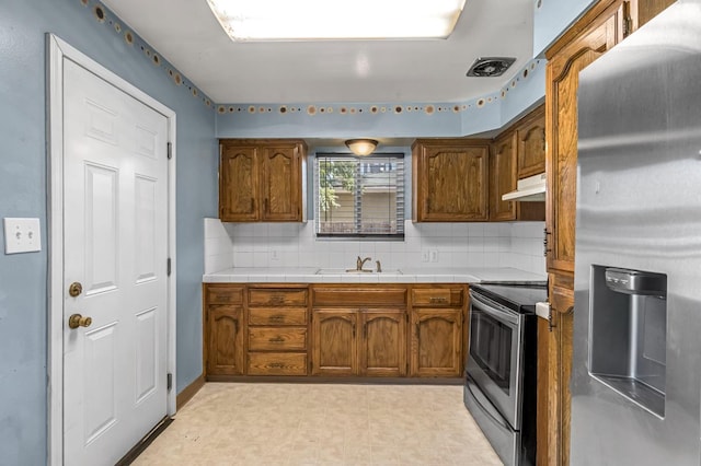 3635 N Hughes, Fresno, CA 93705 - kitchen with appliances with stainless steel finishes, under cabinet range hood, light flooring, backsplash, and brown cabinetry