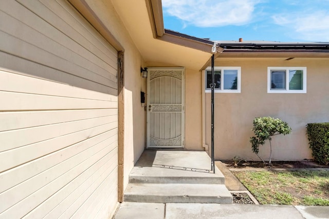 3635 N Hughes, Fresno, CA 93705 - doorway to property featuring stucco siding and solar panels