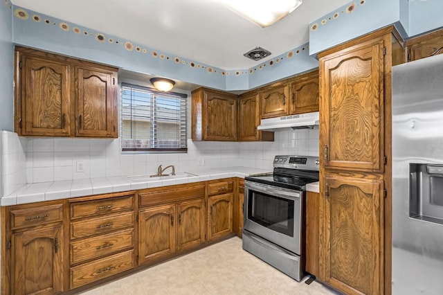 3635 N Hughes, Fresno, CA 93705 - kitchen featuring stainless steel appliances, under cabinet range hood, backsplash, light countertops, and brown cabinets