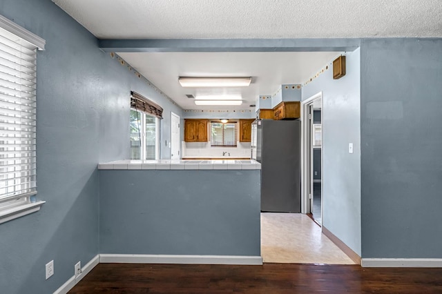 3635 N Hughes, Fresno, CA 93705 - kitchen with freestanding refrigerator, tile countertops, brown cabinetry, a peninsula, and wood finished floors