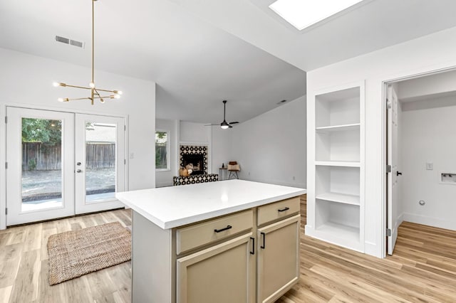 1033 Cypress Ct, Madera, CA 93637 - kitchen with light wood-style floors, a kitchen island, light countertops, a fireplace with raised hearth, and a chandelier