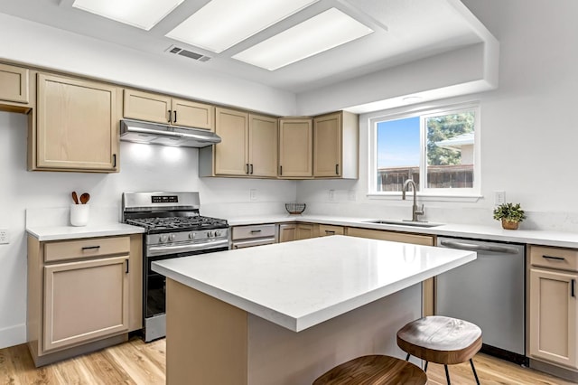 1033 Cypress Ct, Madera, CA 93637 - kitchen with appliances with stainless steel finishes, under cabinet range hood, a breakfast bar, light countertops, and light wood finished floors