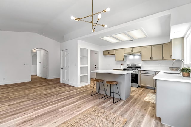 1033 Cypress Ct, Madera, CA 93637 - kitchen with stainless steel gas stove, arched walkways, a kitchen island, lofted ceiling, and a chandelier