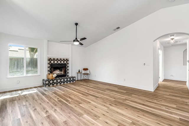 1033 Cypress Ct, Madera, CA 93637 - living room with arched walkways, ceiling fan, lofted ceiling, a tiled fireplace, and wood finished floors