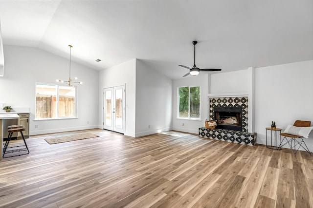 1033 Cypress Ct, Madera, CA 93637 - living room with lofted ceiling, light wood-style floors, ceiling fan, a tile fireplace, and a chandelier