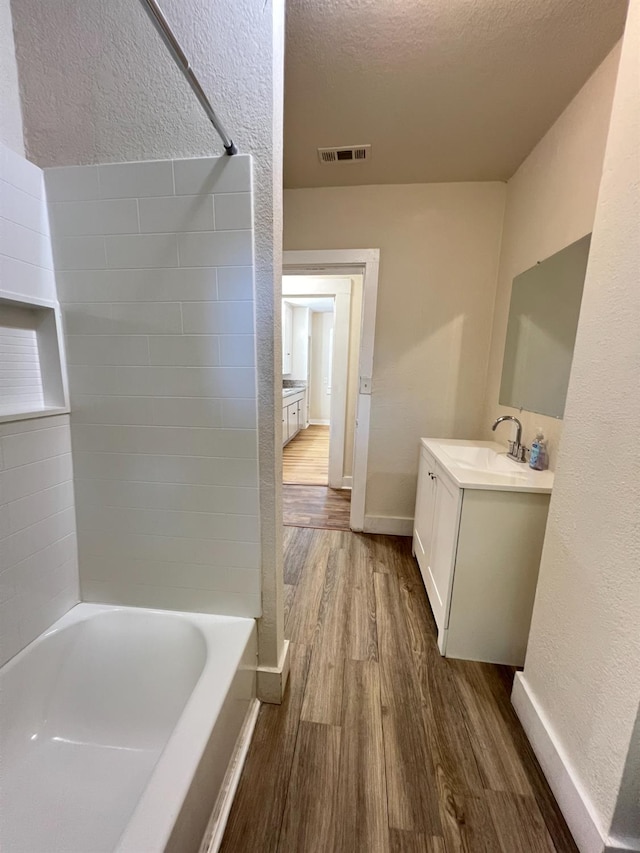 2405 E White Ave, Fresno, CA 93701 - full bathroom featuring wood finished floors, vanity, a textured wall, bathing tub / shower combination, and a textured ceiling
