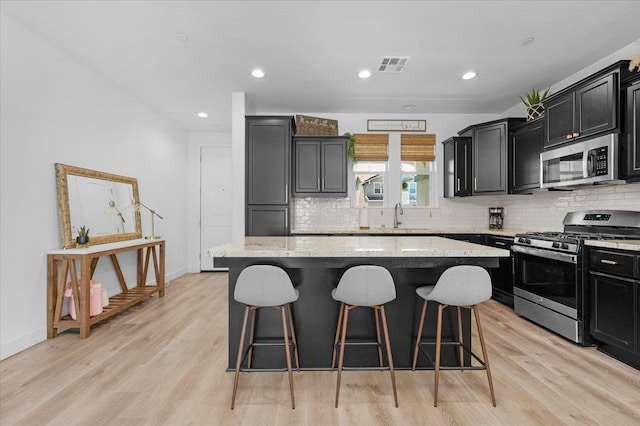 627 S Kandarian Ave, Fowler, CA 93625 - kitchen with appliances with stainless steel finishes, a kitchen bar, a center island, dark cabinets, and tasteful backsplash