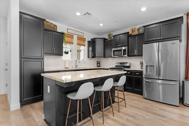 627 S Kandarian Ave, Fowler, CA 93625 - kitchen with stainless steel appliances, a center island, light stone counters, tasteful backsplash, and a breakfast bar