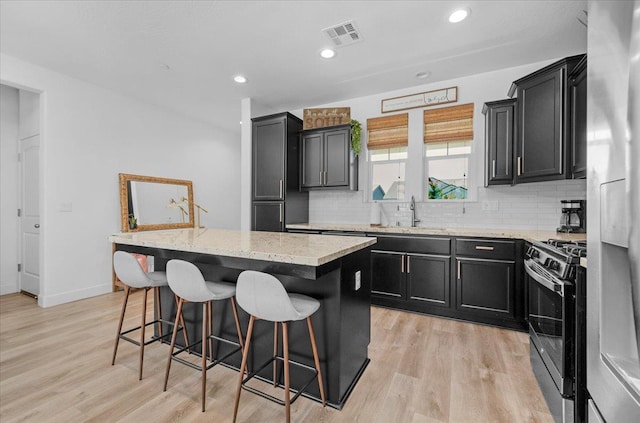 627 S Kandarian Ave, Fowler, CA 93625 - kitchen with stainless steel appliances, a center island, dark cabinets, a breakfast bar area, and recessed lighting