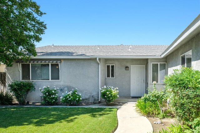 1763 Norwich Ave, Clovis, CA 93611 - doorway to property featuring stucco siding, a yard, and roof with shingles