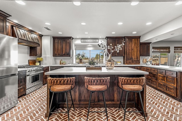 3377 N Bethel Ave, Sanger, CA 93657 - kitchen with appliances with stainless steel finishes, brick floors, dark brown cabinetry, a kitchen island, and recessed lighting