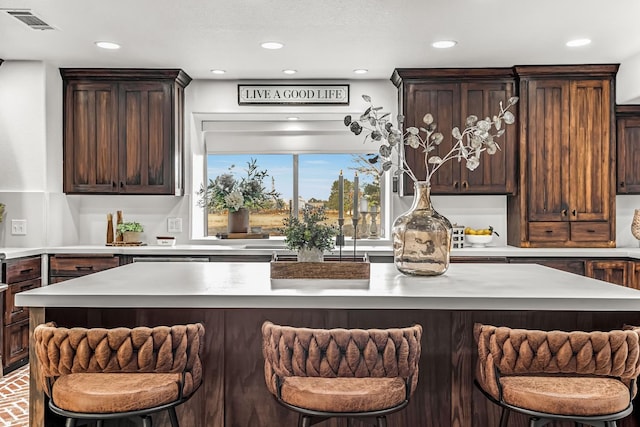 3377 N Bethel Ave, Sanger, CA 93657 - kitchen with light countertops, recessed lighting, a center island, a breakfast bar area, and dark brown cabinetry