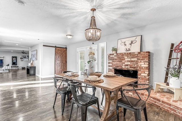 3377 N Bethel Ave, Sanger, CA 93657 - dining space featuring a barn door, a chandelier, wood finished floors, a brick fireplace, and a textured ceiling