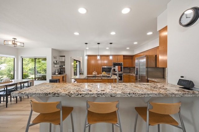 2734 W Bluff Ave, Fresno, CA 93711 - kitchen with brown cabinets, stainless steel appliances, a peninsula, recessed lighting, and light stone countertops