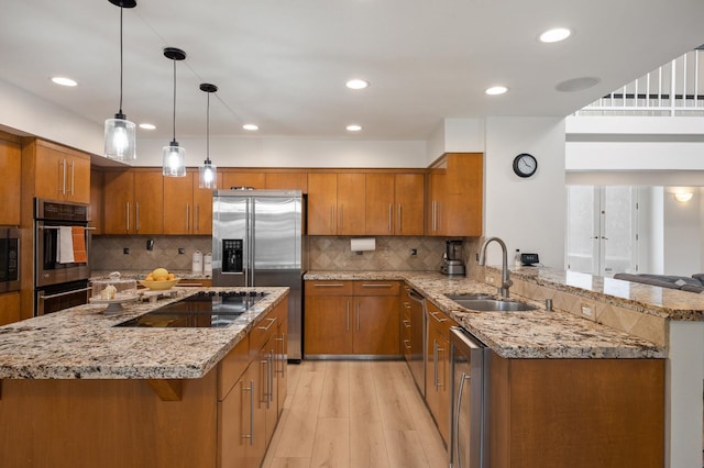 2734 W Bluff Ave, Fresno, CA 93711 - kitchen with brown cabinetry, stainless steel appliances, light wood finished floors, light stone countertops, and a peninsula