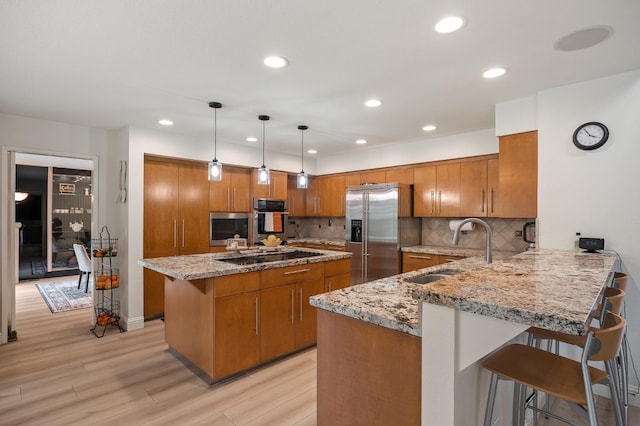 2734 W Bluff Ave, Fresno, CA 93711 - kitchen with appliances with stainless steel finishes, brown cabinetry, light stone countertops, a peninsula, and recessed lighting