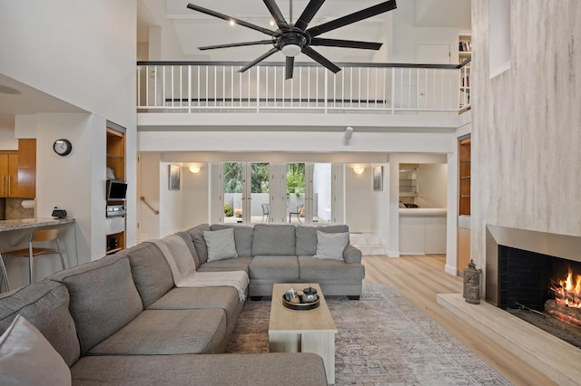 2734 W Bluff Ave, Fresno, CA 93711 - living room with a high ceiling, a ceiling fan, wood finished floors, a warm lit fireplace, and stairway